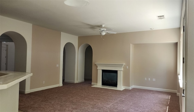 10372 Christo Way, Elk Grove, CA 95757 - unfurnished living room featuring a ceiling fan, carpet flooring, a glass covered fireplace, and arched walkways