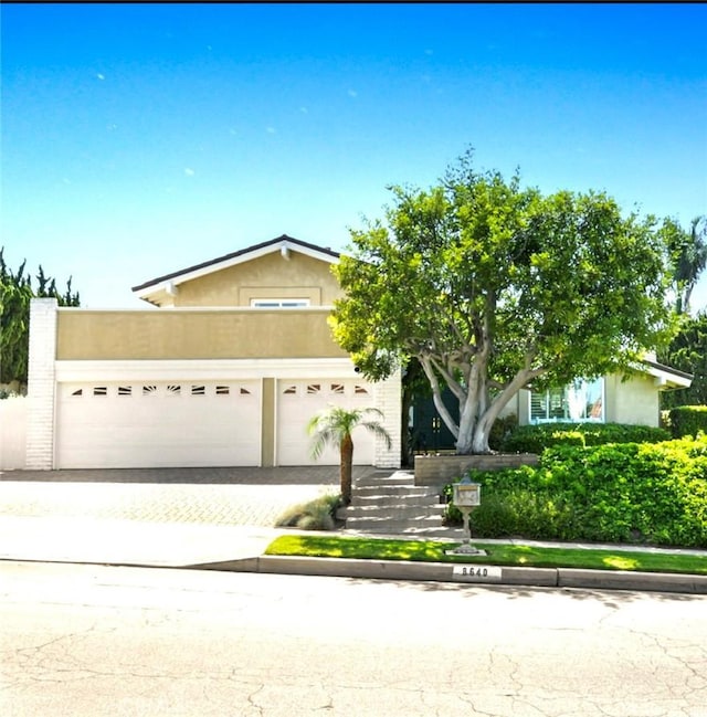 8640 Lindante Dr, Whittier, CA 90603 - view of property hidden behind natural elements featuring stucco siding, a garage, and driveway