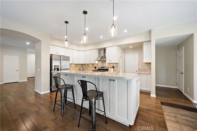 31484 Britton Cir, Temecula, CA 92591 - kitchen featuring wall chimney range hood, appliances with stainless steel finishes, light countertops, arched walkways, and white cabinetry