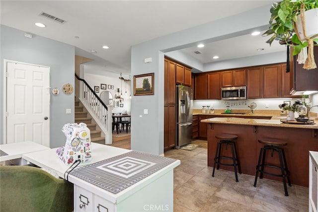 3245 Moss Landing Blvd, Oxnard, CA 93036 - kitchen with stainless steel appliances, a peninsula, a breakfast bar, recessed lighting, and brown cabinets