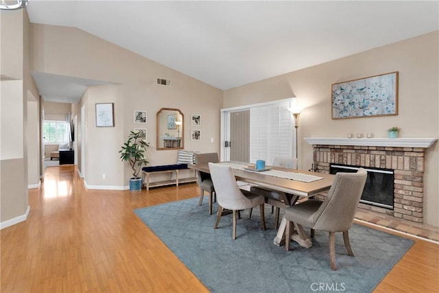 13950 High Falls Trl, Apple Valley, CA 92307 - dining space featuring wood finished floors, a fireplace, high vaulted ceiling, and baseboards