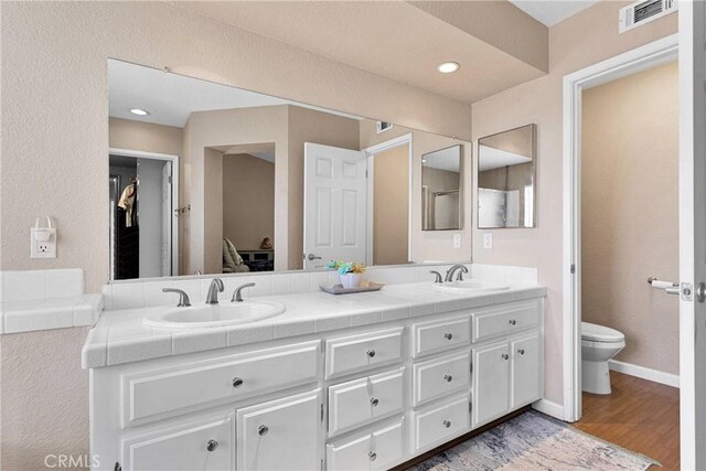 13950 High Falls Trl, Apple Valley, CA 92307 - bathroom with toilet, double vanity, wood finished floors, and baseboards
