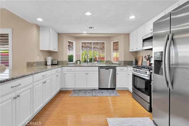 13950 High Falls Trl, Apple Valley, CA 92307 - kitchen with stainless steel appliances, white cabinets, a sink, light wood-style flooring, and recessed lighting