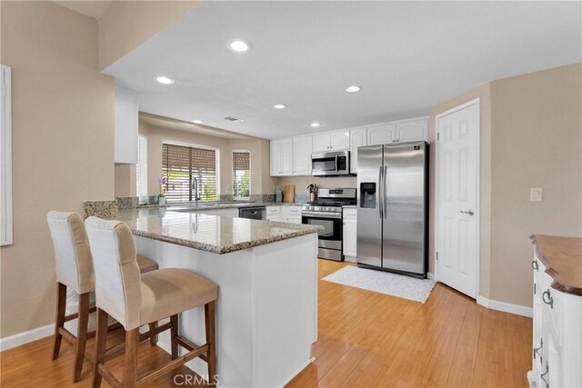 13950 High Falls Trl, Apple Valley, CA 92307 - kitchen with stainless steel appliances, a peninsula, white cabinets, a kitchen breakfast bar, and baseboards