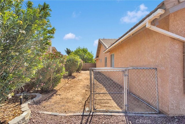 13950 High Falls Trl, Apple Valley, CA 92307 - view of home's exterior with stucco siding, a gate, a fenced backyard, and a tile roof