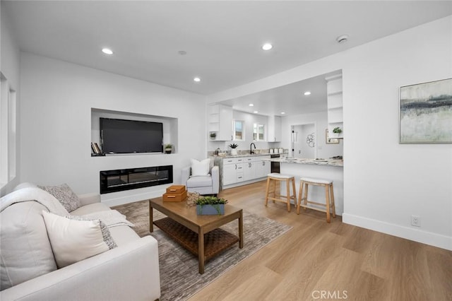 201 S Melrose St, Placentia, CA 92870 - living area with light wood-type flooring, recessed lighting, a glass covered fireplace, and baseboards