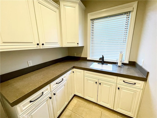 1371 Silhouette Ct, Merced, CA 95340 - kitchen with a sink, dark countertops, light tile patterned flooring, and white cabinetry