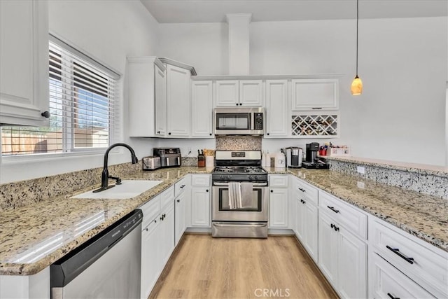 5947 Lupine Ave Unit 29, Palms, CA 92277 - kitchen featuring stainless steel appliances, a sink, white cabinets, light wood-style floors, and light stone counters