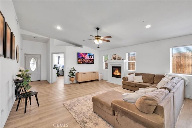 5947 Lupine Ave Unit 29, Palms, CA 92277 - living area with healthy amount of natural light, vaulted ceiling, a ceiling fan, light wood finished floors, and a glass covered fireplace