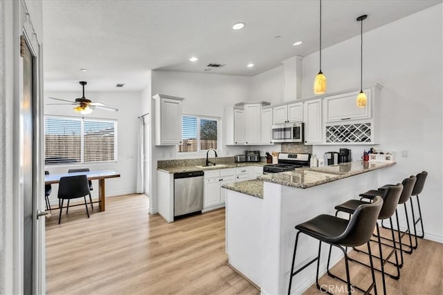 5947 Lupine Ave Unit 29, Palms, CA 92277 - kitchen with appliances with stainless steel finishes, a sink, a peninsula, light wood-type flooring, and light stone countertops