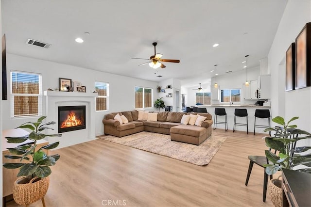 5947 Lupine Ave Unit 29, Palms, CA 92277 - living room featuring a ceiling fan, light wood finished floors, a glass covered fireplace, and recessed lighting