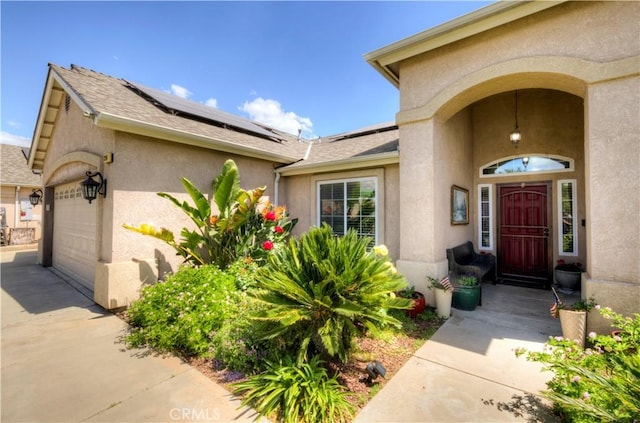 2267 Lorena Ave, Sanger, CA 93657 - view of exterior entry featuring stucco siding, a garage, solar panels, and concrete driveway