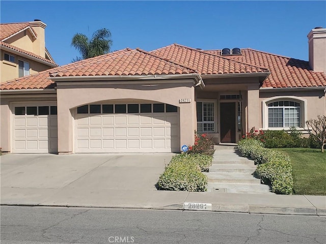 28291 La Plumosa, Laguna Niguel, CA 92667 - mediterranean / spanish-style house featuring a garage, driveway, a chimney, stucco siding, and a tiled roof