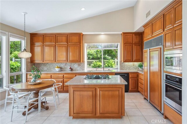 28291 La Plumosa, Laguna Niguel, CA 92667 - kitchen featuring built in appliances, vaulted ceiling, a kitchen island, tasteful backsplash, and plenty of natural light