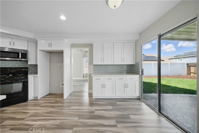 31070 Larchwood St, Menifee, CA 92584 - kitchen featuring stainless steel microwave, black range with gas cooktop, backsplash, white cabinets, and recessed lighting