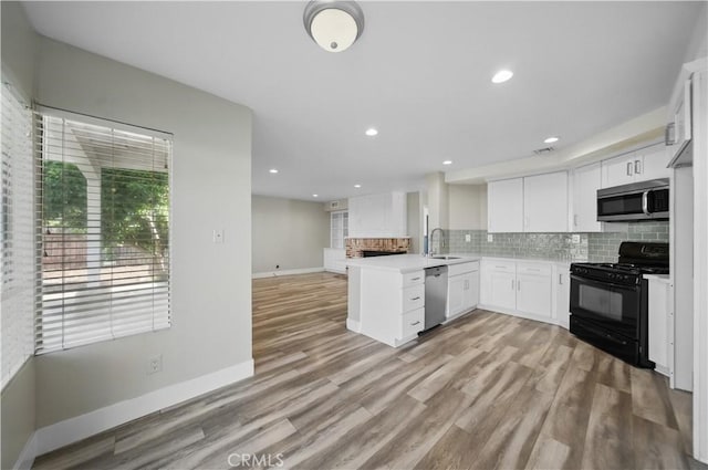 31070 Larchwood St, Menifee, CA 92584 - kitchen featuring stainless steel appliances, a peninsula, white cabinets, decorative backsplash, and light wood-style flooring