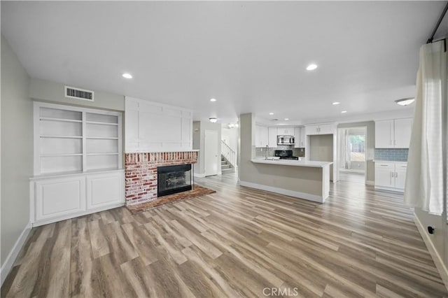31070 Larchwood St, Menifee, CA 92584 - unfurnished living room with a brick fireplace, light wood-style floors, recessed lighting, and stairs