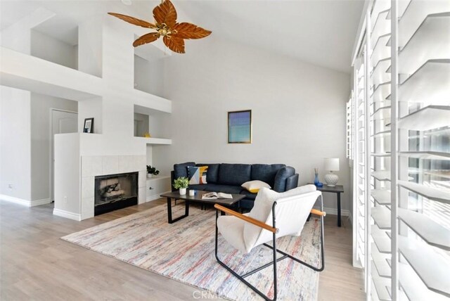 1272 Avenida Roundelay, San Jacinto, CA 92583 - living area featuring wood finished floors, baseboards, a fireplace, a ceiling fan, and a towering ceiling