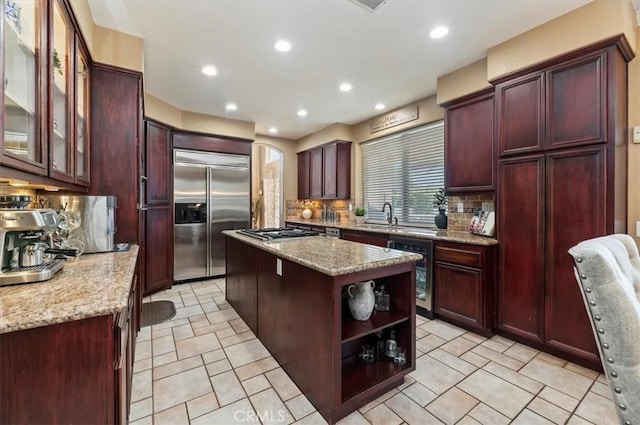 23328 Stone Rdg, Murrieta, CA 92562 - kitchen with appliances with stainless steel finishes, dark brown cabinets, a kitchen island, tasteful backsplash, and light stone countertops