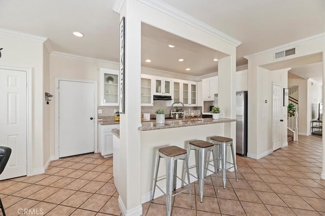 24320 Calle Estancia, Murrieta, CA 92562 - kitchen with freestanding refrigerator, tasteful backsplash, white cabinets, a kitchen bar, and glass insert cabinets