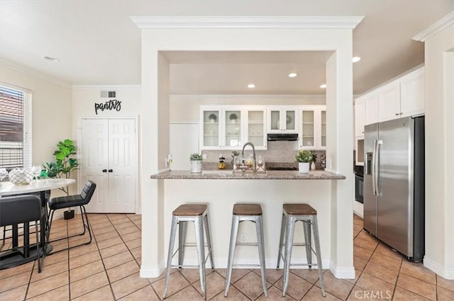24320 Calle Estancia, Murrieta, CA 92562 - kitchen featuring stainless steel fridge, light tile patterned floors, a breakfast bar, under cabinet range hood, and backsplash