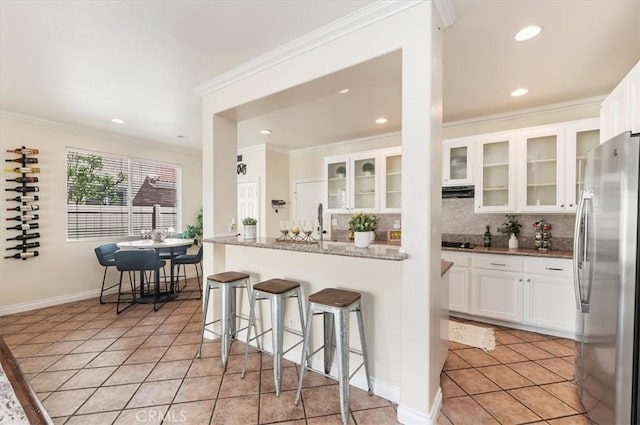 24320 Calle Estancia, Murrieta, CA 92562 - kitchen featuring freestanding refrigerator, a kitchen breakfast bar, decorative backsplash, crown molding, and light tile patterned floors