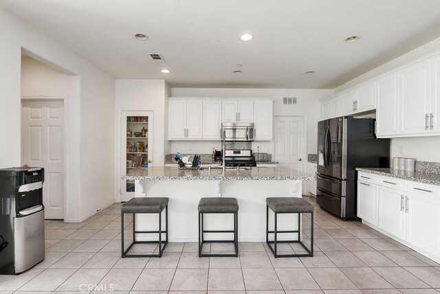 706 Leather Oak Ln, Pomona, CA 91766 - kitchen featuring appliances with stainless steel finishes, white cabinetry, a kitchen breakfast bar, light stone countertops, and recessed lighting