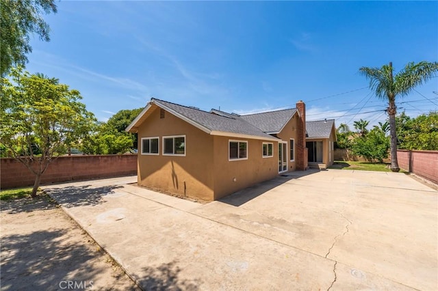 404 N Pear Knl, Anaheim, CA 92805 - back of property featuring stucco siding, a fenced backyard, a patio, and a chimney