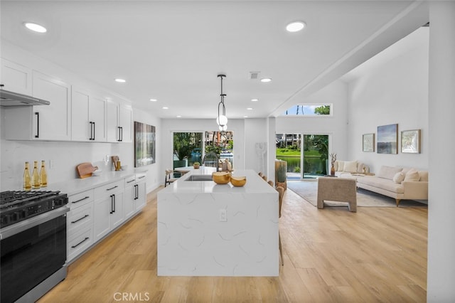 22526 Lake Forest Ln, Lake Forest, CA 92630 - kitchen with gas stove, a sink, white cabinets, recessed lighting, and a kitchen island with sink