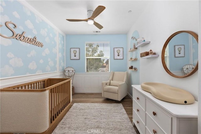 1733 San Eugenio, San Diego, CA 92154 - bedroom featuring a nursery area, wood finished floors, wainscoting, and a ceiling fan