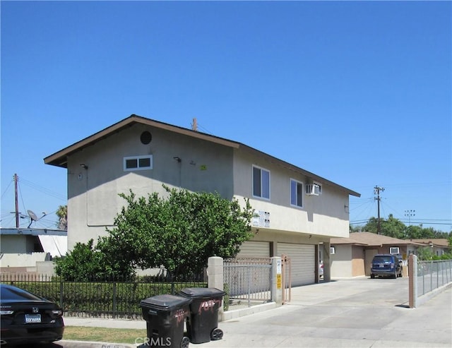 7010 Granger Ave, Bell Gardens, CA 90201 - view of side of property with stucco siding, concrete driveway, an attached garage, and a wall unit AC