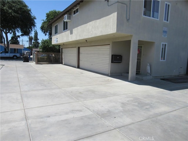 7010 Granger Ave, Bell Gardens, CA 90201 - view of side of property featuring stucco siding, a garage, driveway, and a wall unit AC