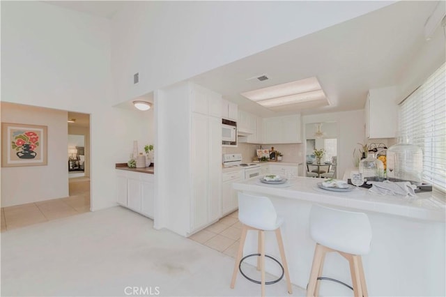 2501 Tiffany Pl, Fullerton, CA 92833 - kitchen featuring white appliances, a peninsula, white cabinetry, and a kitchen bar