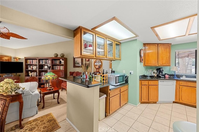 27525 Ventura Dr, Cathedral City, CA 92234 - kitchen featuring white dishwasher, stainless steel microwave, dark countertops, glass insert cabinets, and light tile patterned flooring