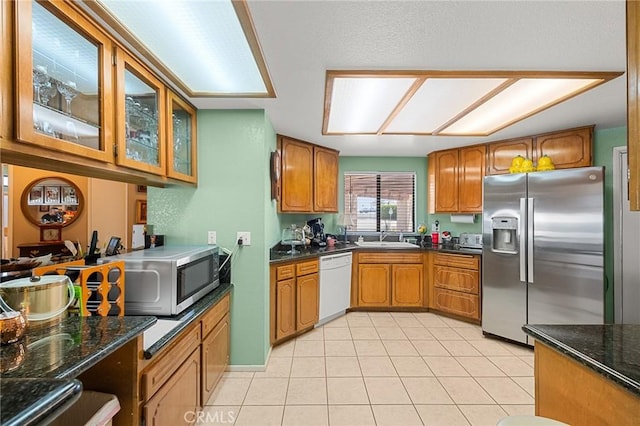 27525 Ventura Dr, Cathedral City, CA 92234 - kitchen with appliances with stainless steel finishes, brown cabinets, light tile patterned floors, glass insert cabinets, and a sink