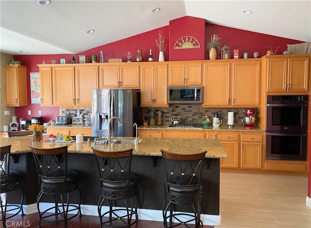 757 Onstott Rd, Lompoc, CA 93436 - kitchen featuring stainless steel appliances, vaulted ceiling, light wood-style flooring, decorative backsplash, and a breakfast bar area