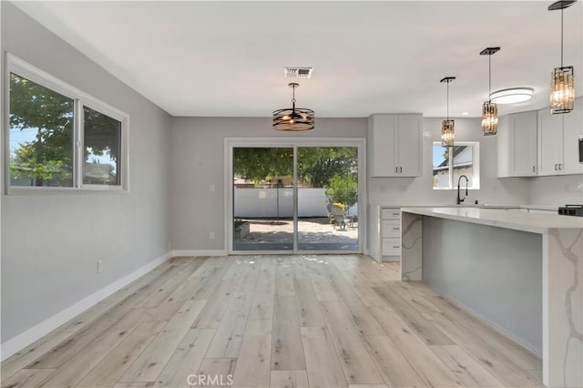 7741 Shoup Ave, West Hills, CA 91304 - kitchen featuring light countertops, light wood-style flooring, baseboards, a sink, and hanging light fixtures