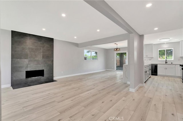 7741 Shoup Ave, West Hills, CA 91304 - unfurnished living room with light wood-style floors, recessed lighting, baseboards, a tile fireplace, and a sink
