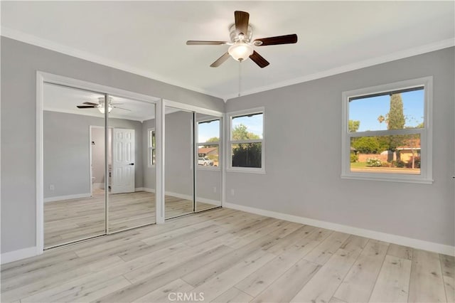 7741 Shoup Ave, West Hills, CA 91304 - unfurnished bedroom with two closets, baseboards, multiple windows, wood finished floors, and crown molding
