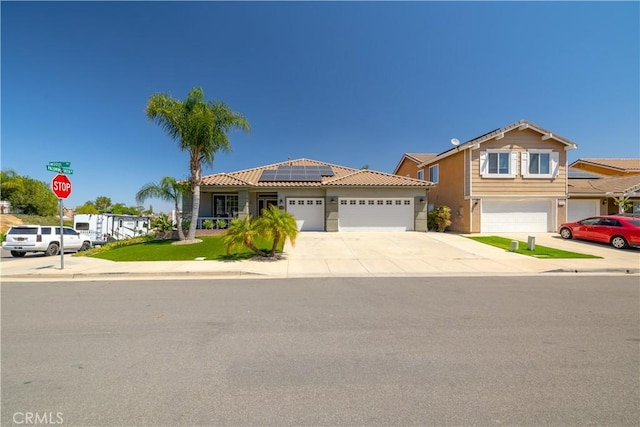 13946 Moqui Way, Corona, CA 92883 - view of front of house with solar panels, driveway, an attached garage, stucco siding, and a tiled roof