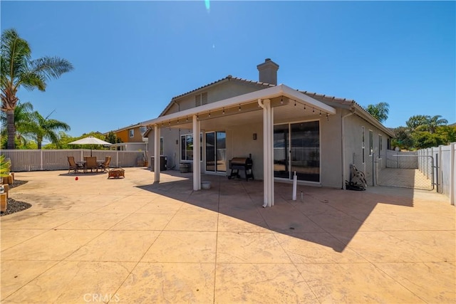 13946 Moqui Way, Corona, CA 92883 - rear view of property with stucco siding, a patio, a tiled roof, a fenced backyard, and a chimney