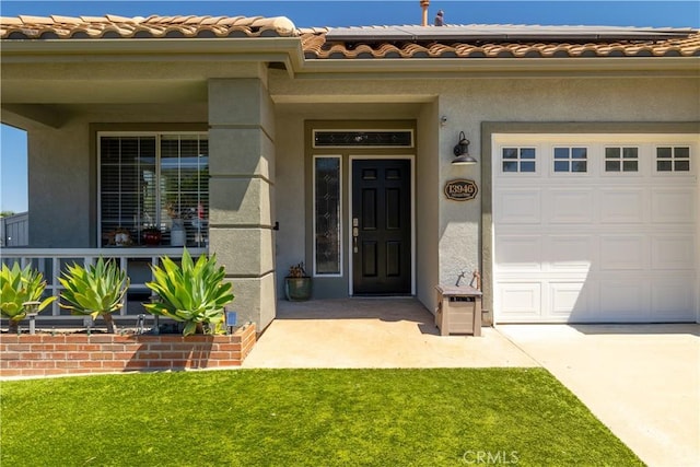 13946 Moqui Way, Corona, CA 92883 - view of exterior entry featuring stucco siding, driveway, a tiled roof, a yard, and an attached garage