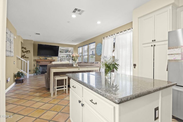 1269 Hacienda Dr, Oxnard, CA 93030 - kitchen with a center island, white cabinetry, stone counters, baseboards, and a fireplace