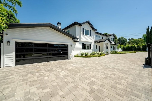 20701 Dumont St, Woodland Hills, CA 91364 - view of front facade featuring decorative driveway, a garage, and a chimney