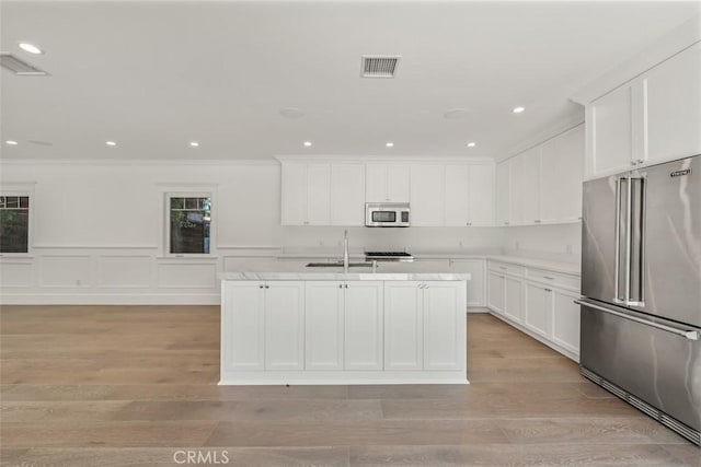 20701 Dumont St, Woodland Hills, CA 91364 - kitchen featuring appliances with stainless steel finishes, a sink, light countertops, white cabinetry, and an island with sink