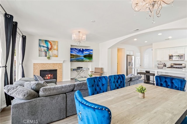 84020 Colibri Ct, Indio, CA 92203 - dining room featuring a chandelier, arched walkways, light wood finished floors, a glass covered fireplace, and recessed lighting