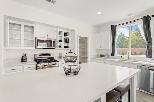 84020 Colibri Ct, Indio, CA 92203 - kitchen with appliances with stainless steel finishes, a sink, a breakfast bar, white cabinetry, and recessed lighting