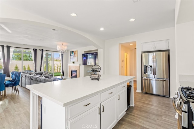 84020 Colibri Ct, Indio, CA 92203 - kitchen with appliances with stainless steel finishes, a glass covered fireplace, arched walkways, white cabinetry, and open floor plan