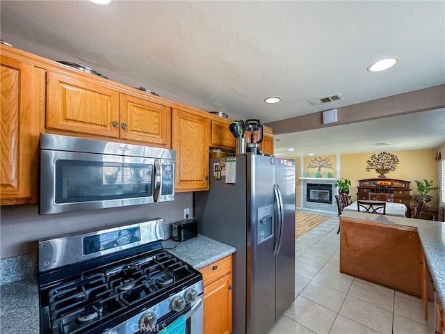 45431 Sancroft Ave, Lancaster, CA 93535 - kitchen with stainless steel appliances, recessed lighting, open floor plan, light tile patterned flooring, and brown cabinets