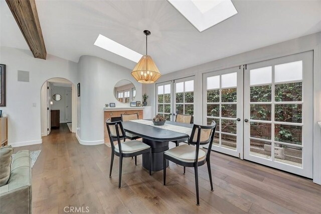 306 Avenida Monterey, San Clemente, CA 92672 - dining room featuring a skylight, a chandelier, arched walkways, wood finished floors, and lofted ceiling